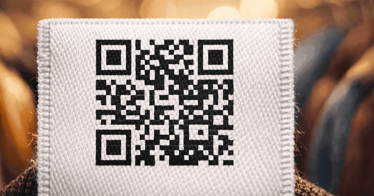 Close-up of QR code on a woven care label with garments in background